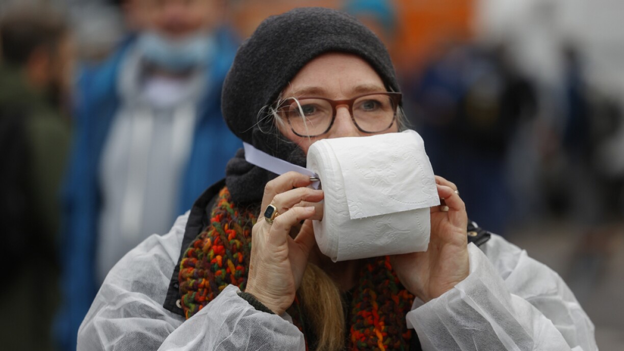 A demonstrator wears a toilet paper roll instead of a protective face mask during a protest against measures imposed by the German government to limit the spread of the novel coronavirus, on November 18, 2020 near the Brandenburg Gate in Berlin. German MPs are to pass new restrictions to keep the pandemic in check. Militant opponents of Germany's measures to halt the spread of coronavirus were barred from marching outside parliament over fears of violence.