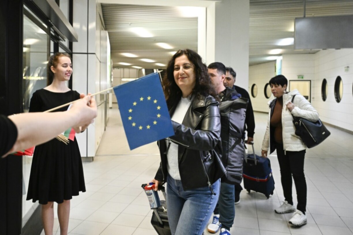 Des passagers arrivant de Berlin recoivent des drapeaux européen et bulgare après l'entrée partielle de la Bulgarie dans l'espace Schengen, à l'aéoport de Sofia le 31 mars 2024
