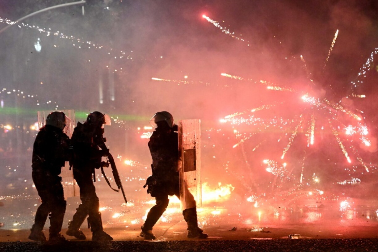 Riot police officers take cover as protesters throw molotov cocktail during an anti-government demonstration in central Tirana on October 18, 2026, as protests continued for a sixth consecutive day over university conditions and demands for the resignation of Albania's Prime Minister. Albanian police fired water cannon and tear gas on October 18, 2026, as violent anti-government protests entered a sixth day and Prime Minister rejected demonstrators demands that he resign.
