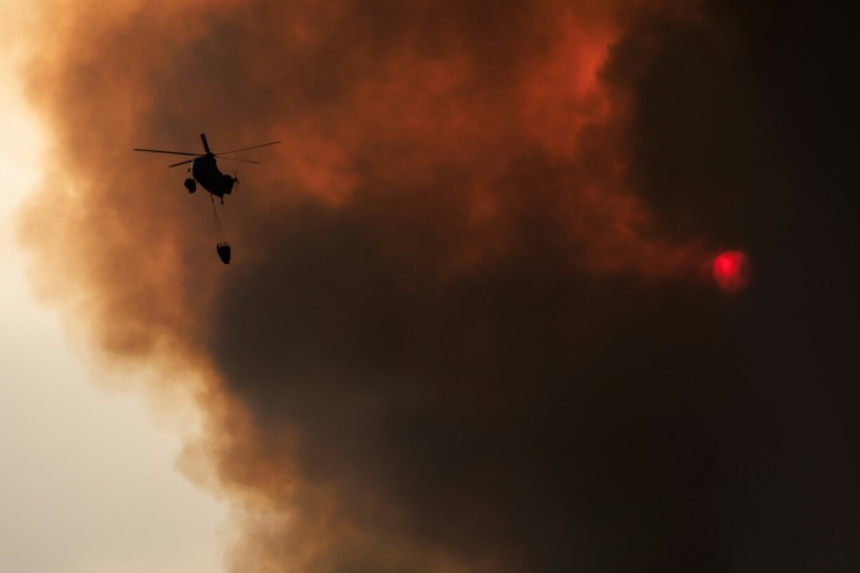 Officials have warned that high winds and rising temperatures were hindering efforts to put out the blazes