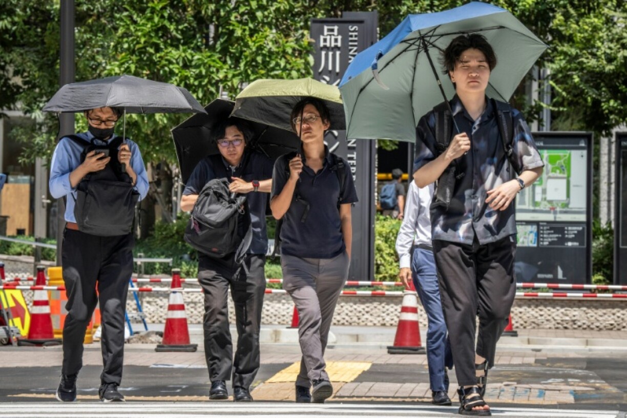 People shield themselves from the hot sun with umbrellas in Tokyo on August 27, 2025