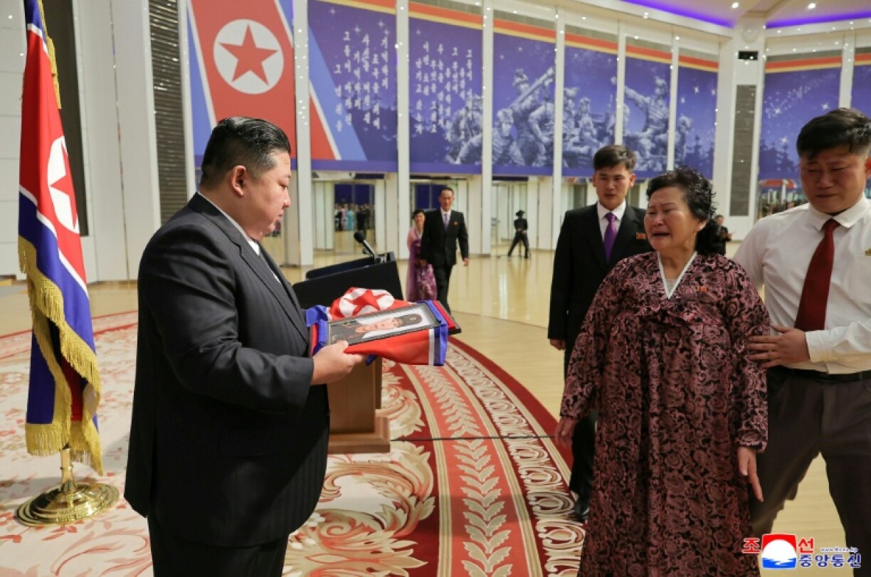 This picture released by North Korea's official Korean Central News Agency (KCNA) on August 30, 2025 shows Kim Jong Un handing over a portrait wrapped in a flag to the family of a soldier