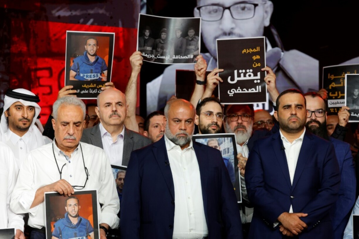 Wael Al-Dahdouh, Al Jazeera's Gaza bureau chief, stands with anchor and presenter Mohamed Krichen and presenter Tamer Almisshal during a moment of silence to honour five of their colleagues killed in an overnight Israeli strike in Gaza City