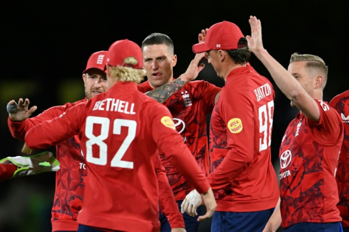 England's Brydon Carse (C) celebrates with teammates after taking the wicket of New Zealand's Rachin Ravindra