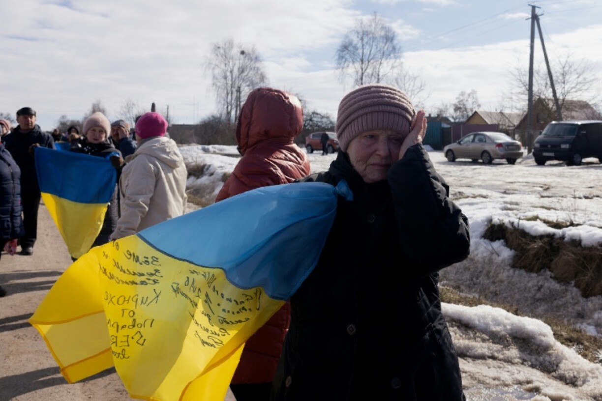 Une femme en larmes sur le bord de la route au passage d'un convoi de soldats ukrainiens libérés par les Russes après un échange de prisonniers, le 6 mars 2026 dans un lieu non précisé dans le nord de l'Ukraine
