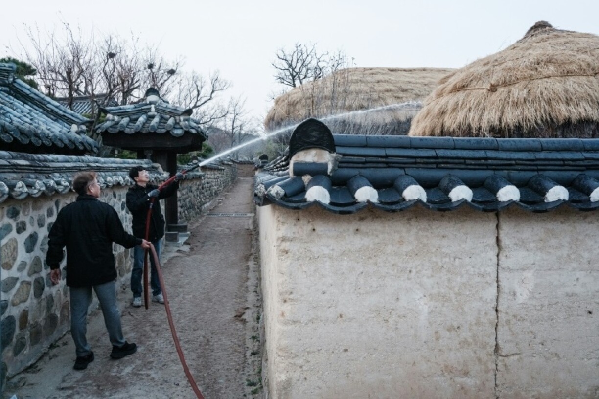 Firefighters are spraying water on thatched roofs in Hahoe Folk Village, which is UNESCO listed