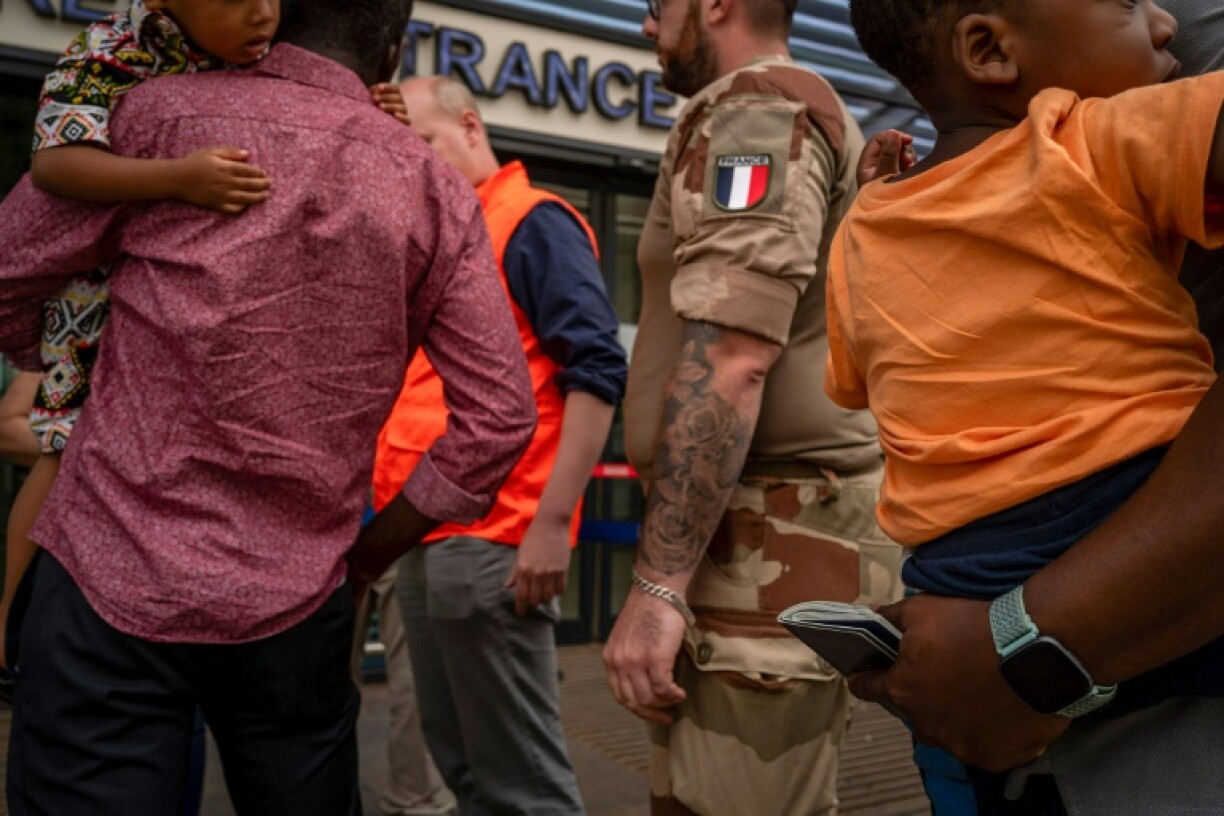 Un soldat français avec des passagers devant l'aéroport international Diori Hamani de Niamey le 2 août 2023