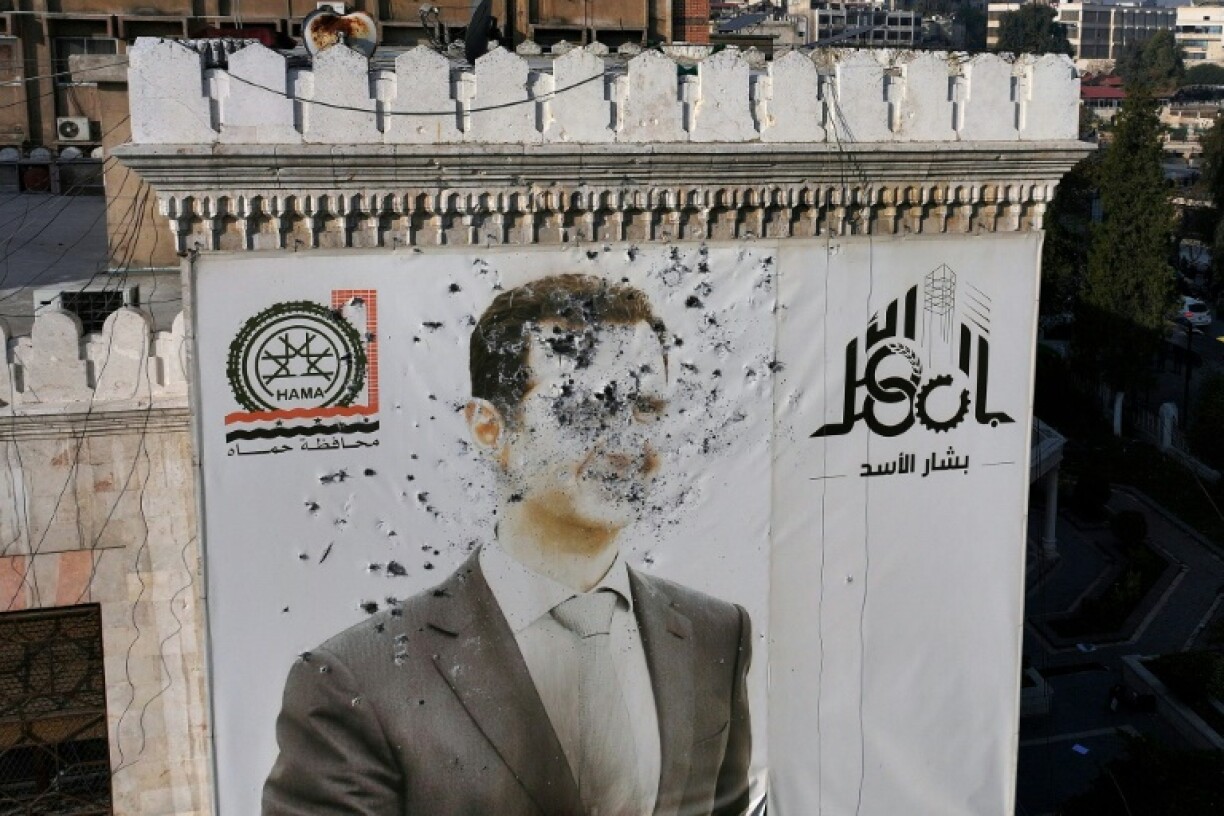 Rebel bullets riddle a portrait of Syrian President Bashar al-Assad on the facade of city hall in Hama