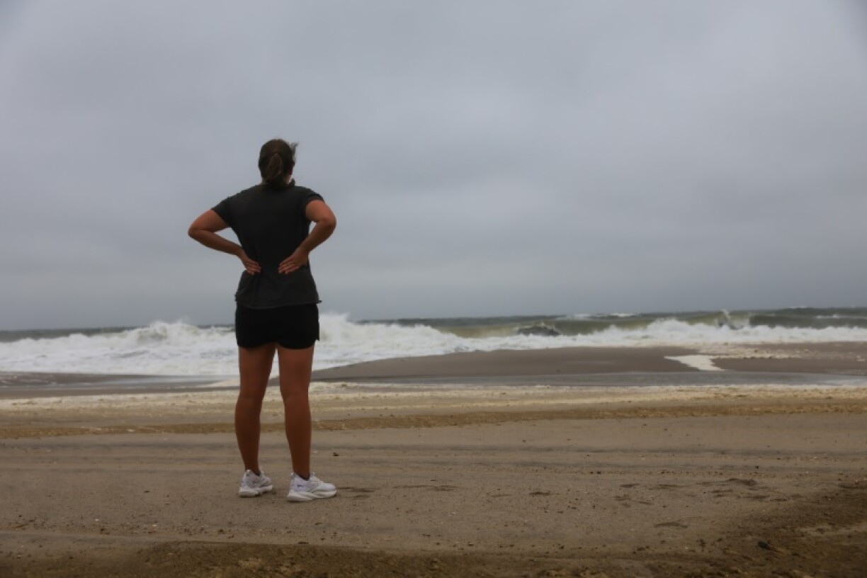 A person looks out at the ocean as large waves from Hurricane Erin keep swimmers away on August 21, 2025, in Seaside Heights, New Jersey