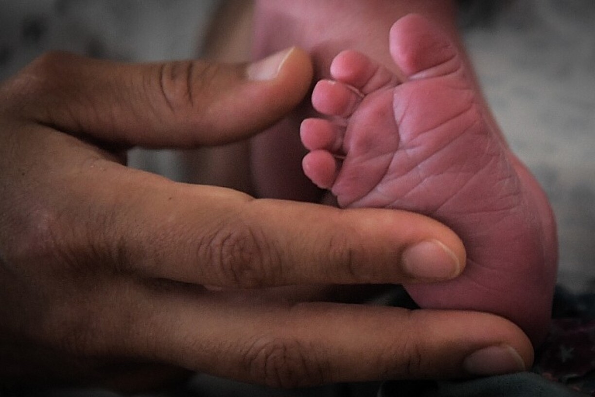 A mother holds the foot of her newborn baby in 2019