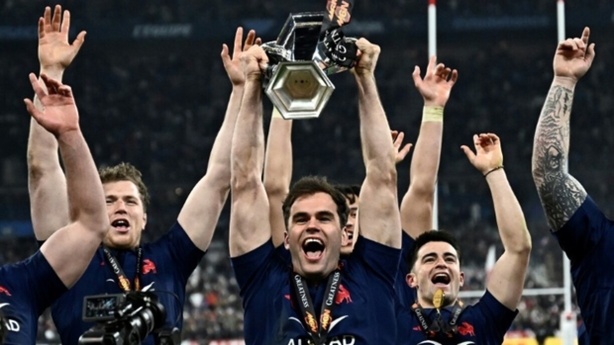 L'ailier français Damian Penaud (C) tient le trophée alors que les joueurs de rugby français fêtent leur victoire dans le Tournoi des six nations 2025 après leur victoire contre l'Ecosse, au stade de France, le 15 mars 2025