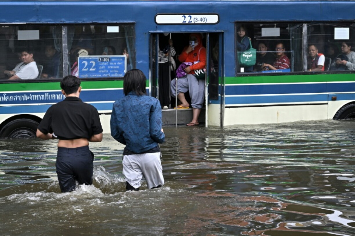 People wade through floodwater to embark on a public bus on Ramkhamhaeng road at Bang Kapi district in Bangkok