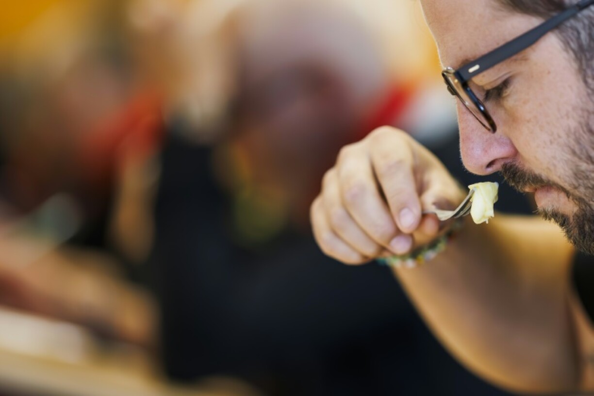 Un juré des premiers championnats du monde de la raclette sent un morceau de fromage, à Morgins, en Suisse, le 28 octobre 2023