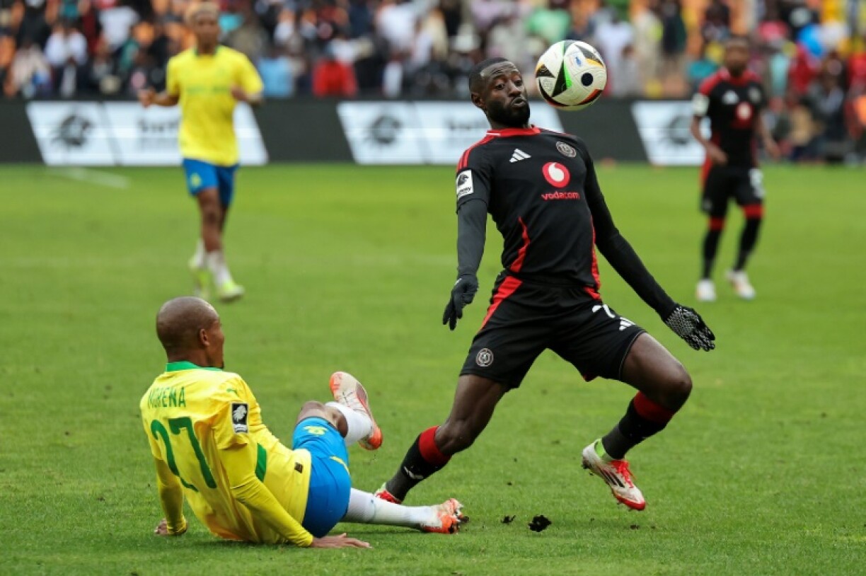 Deon Hotto (R) controls the ball watched by fallen Khuliso Mudau of Mamelodi Sundowns during a South African Premiership match in Johannesburg on March 16, 2025.