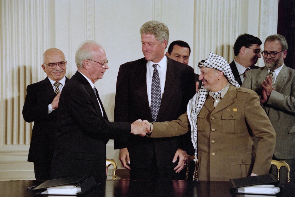 US President Bill Clinton observes as Israeli Prime Minister Yitzhak Rabin and PLO Chairman Yasser Arafat shake hands after signing an accord for Palestinian autonomy in the West Bank during ceremonies at the white House in Washington DC on 28 September 1995.