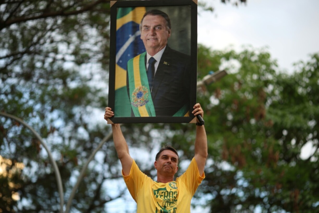 The shock first-place finish by his eldest son Flavio (holding his picture) in Sunday's opening-round election offered a touch of vindication for former president Jair Bolsonaro