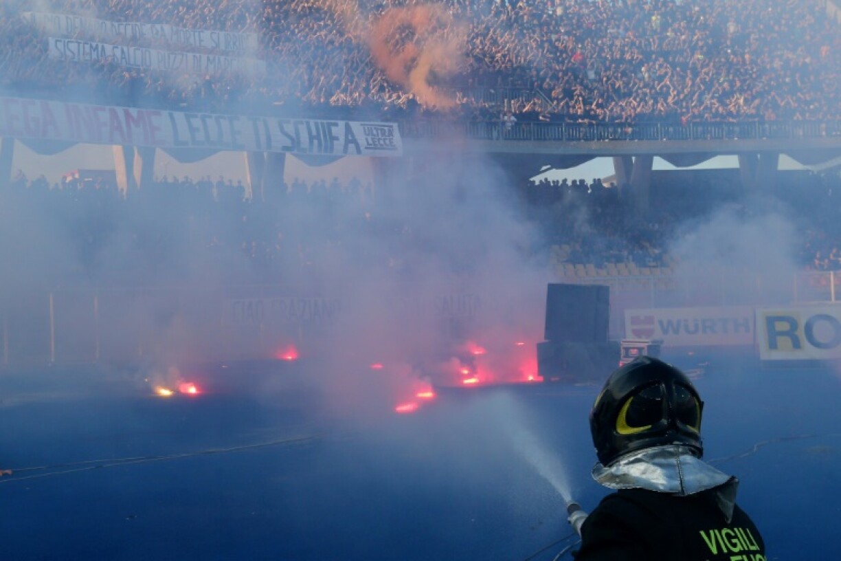 A firefighter puts out flares thrown onto the pitch by Lecce fans