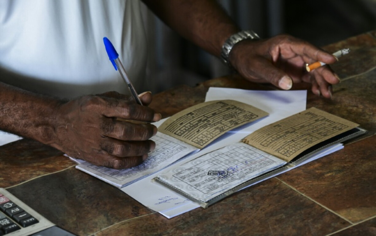 An employee in a Cuban state-run grocery store examines a ration book, a disappearing symbol of a crumbling communist economy