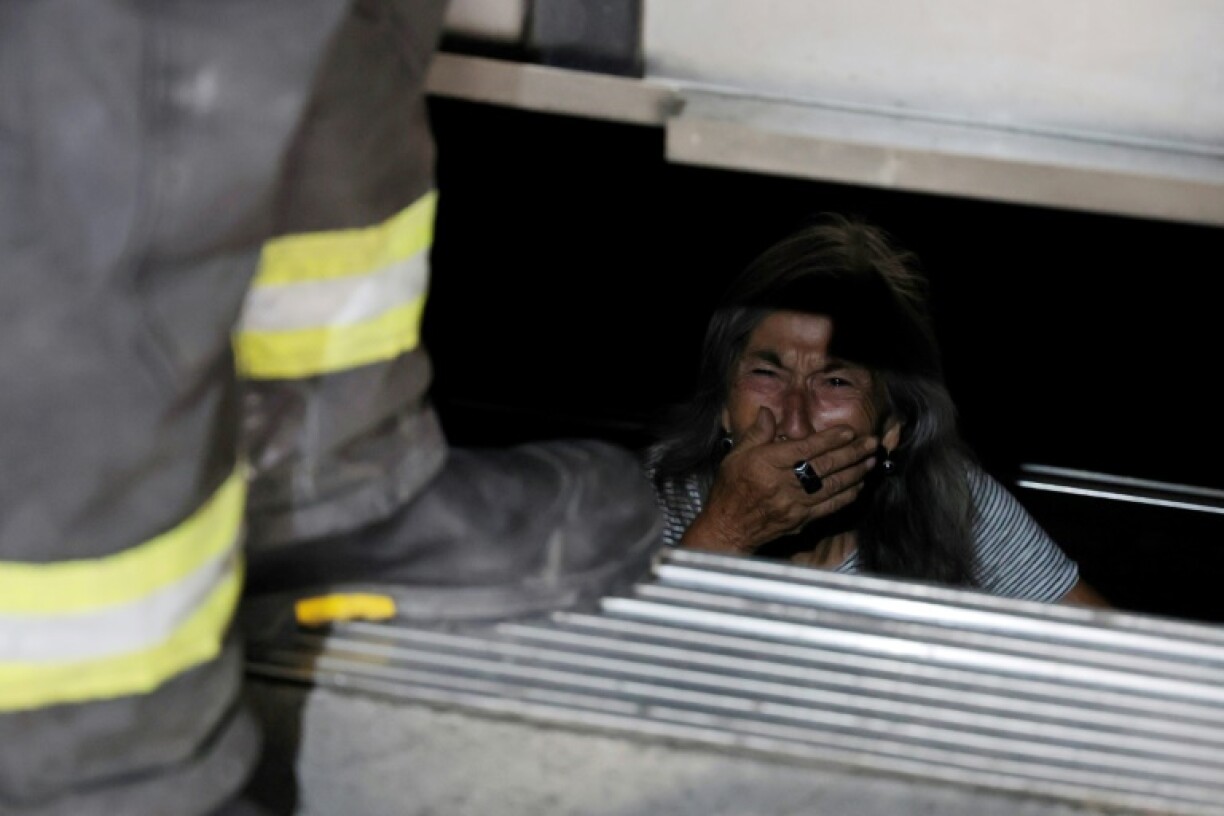 An elderly person trapped in an elevator is assisted by firefighters during a blackout in Santiago