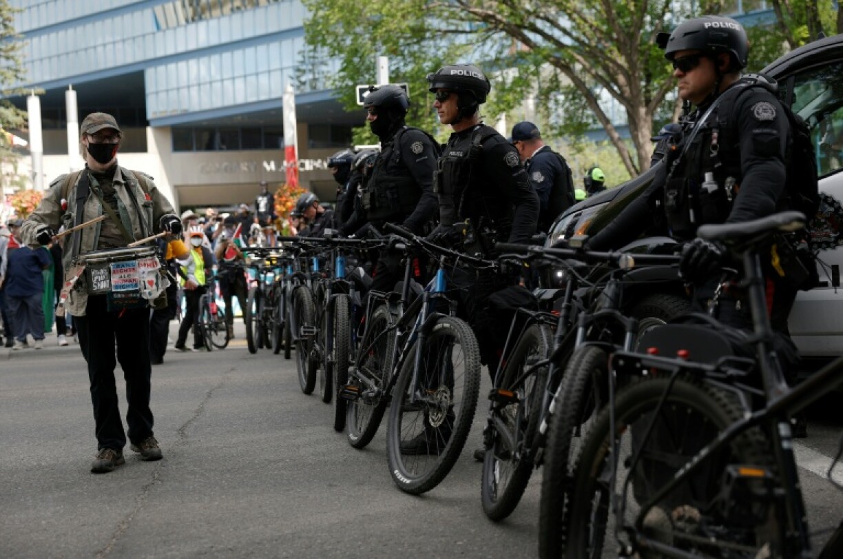 A protester beats on a drum in front of a line of police during a demonstration in front of Calgary City Hall on June 15, 2025, as world leaders converge in Canada for the G7 Summit