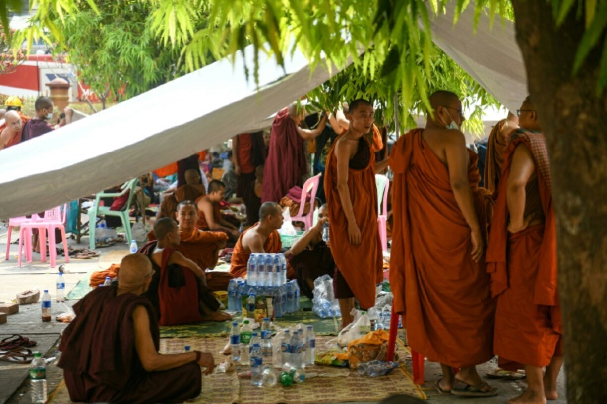 Monks wait during search and rescue operations after the devastating earthquake hit Myanmar's Manadalay city