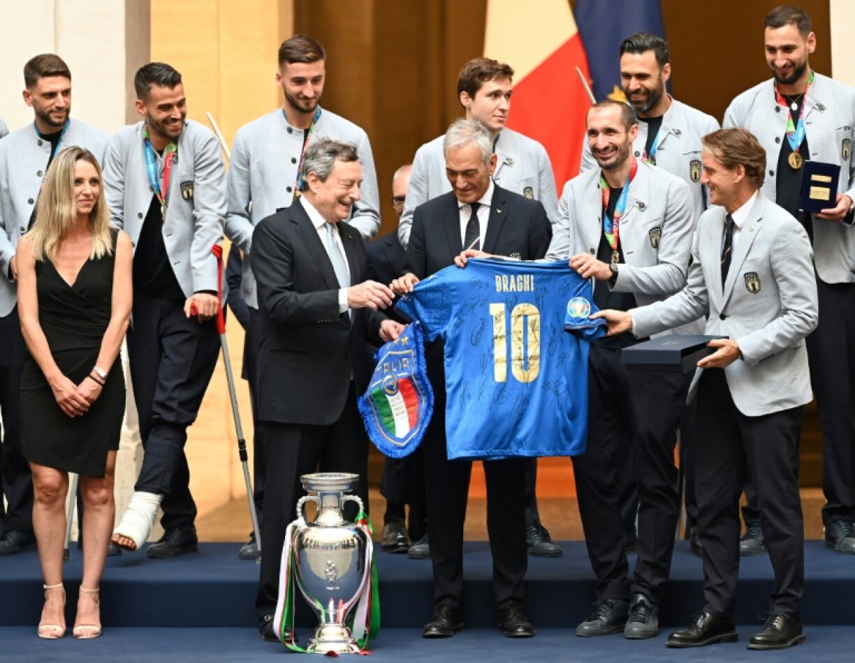 Le sélectionneur italien Roberto Mancini (droite) offre un maillot des Azzurri au Premier ministre Mario Draghi (gauche) à Rome, le 12 juillet 2021