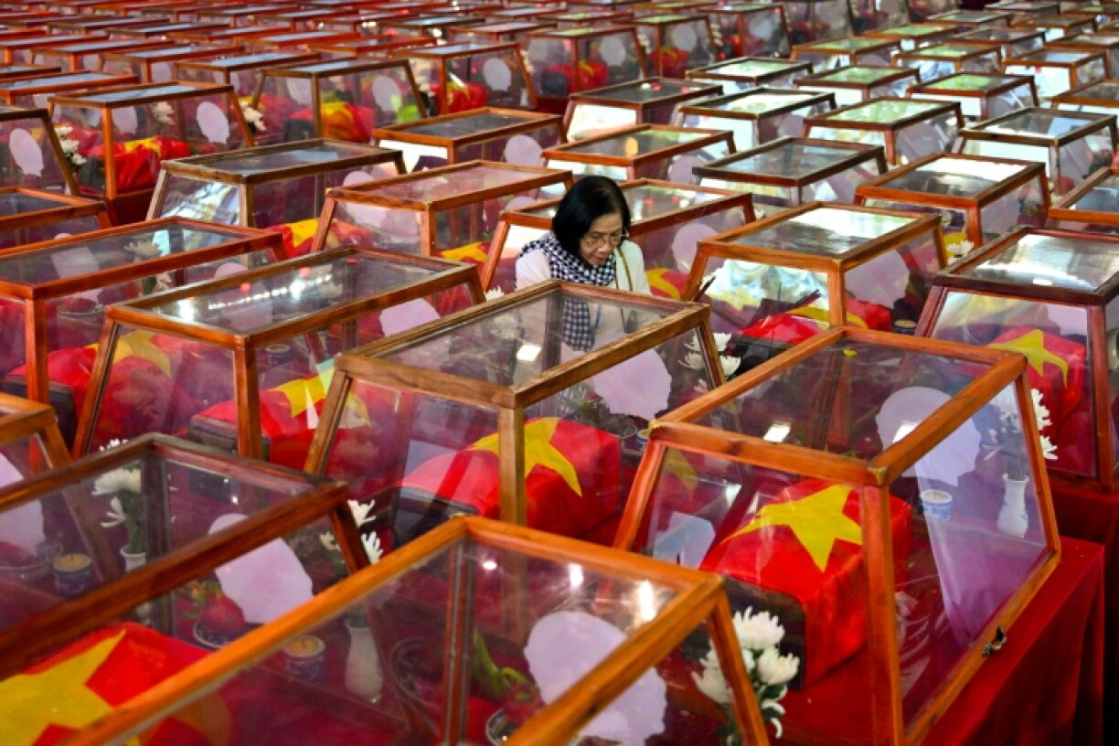 A woman stands beside caskets bearing the remains of fallen soldiers at Le Thi Rieng Park in Ho Chi Minh City