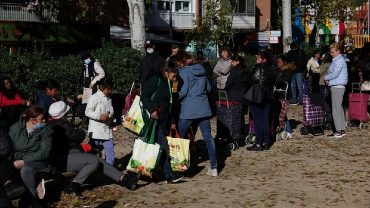 Des habitants attendent pour aller chercher de la nourriture devant le local de l'association du quartier Aluche à Madrid le 19 novembre 2022
