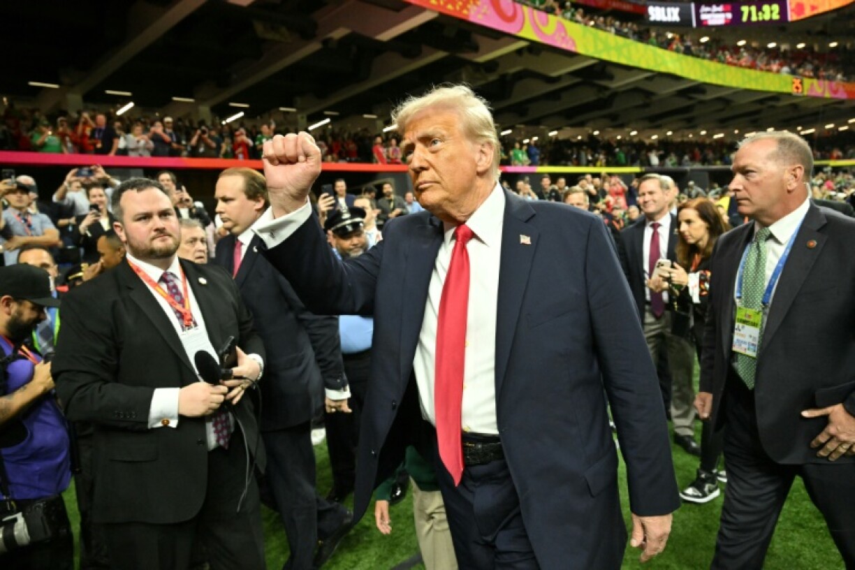 US President Donald Trump salutes the crowd from the field at the New Orleans Superdome at Sunday's Super Bowl