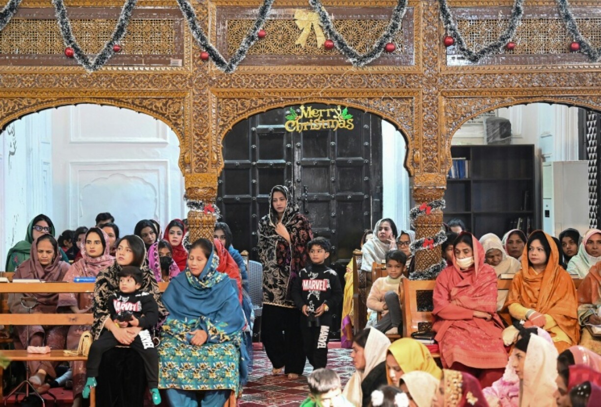 Natasha Zulfiqar (c), femme au foyer blessée avec ses parents dans un attentat meurtrier, arrive avec son fils pour prier à l'église All Saints de Peshawar à l'occasion de Noël, le 25 décembre 2025 au Pakistan