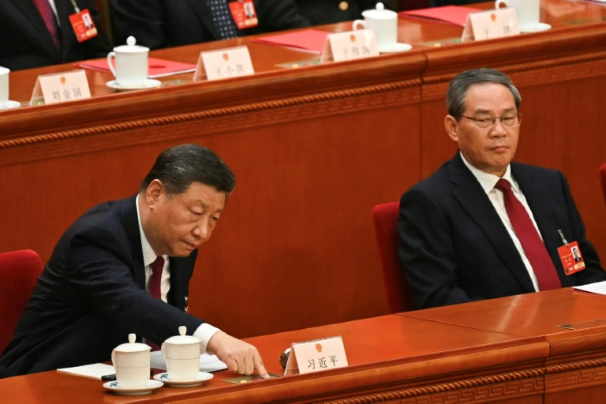 China's President Xi Jinping (L) votes as Premier Li Qiang looks on during the closing session of the National People's Congress in Beijing