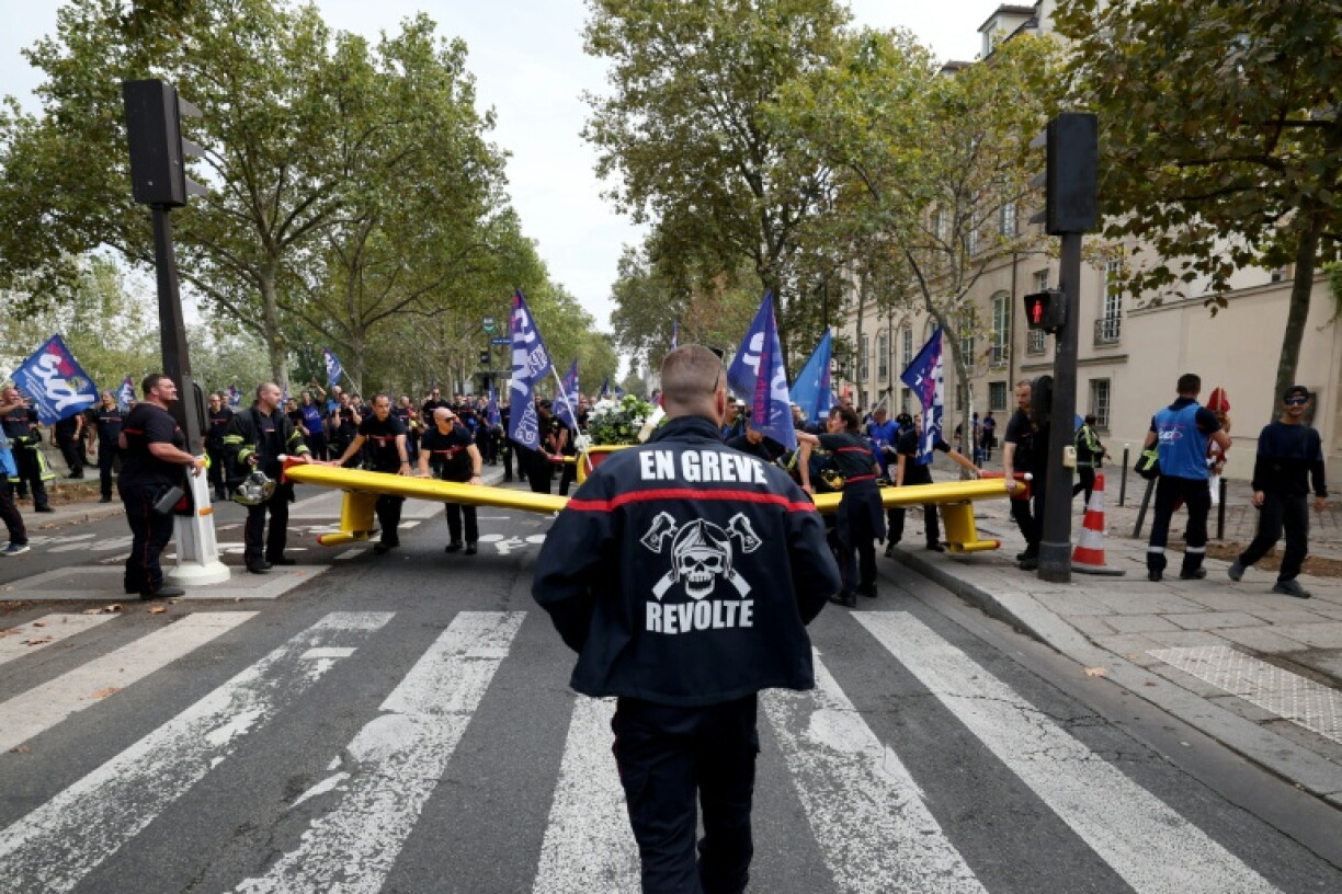 Un pompier portant une inscription "En grève" participe à une manifestation organisée par une large coalition de syndicats, à Paris, le 28 septembre 2026