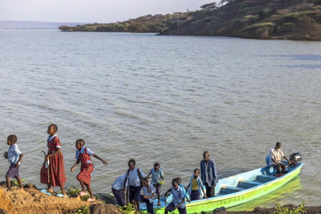 Des élèves rejoignent leur école en bateau, le 28 juillet 2026, sur le lac Bogoria, au Kenya, dont la montée des eaux a submergé le passage habituellement emprunté