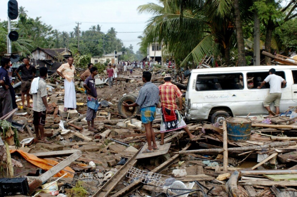 Sri Lankan residents pick throught debris caused by a massive tidal wave in the southern district of Galle, December 27, 2004