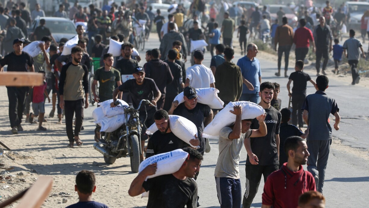 Displaced Palestinians ferry bags of food aid after storming a World Food Programme warehouse in Deir el-Balah in the central Gaza Strip on 28 May 2025.