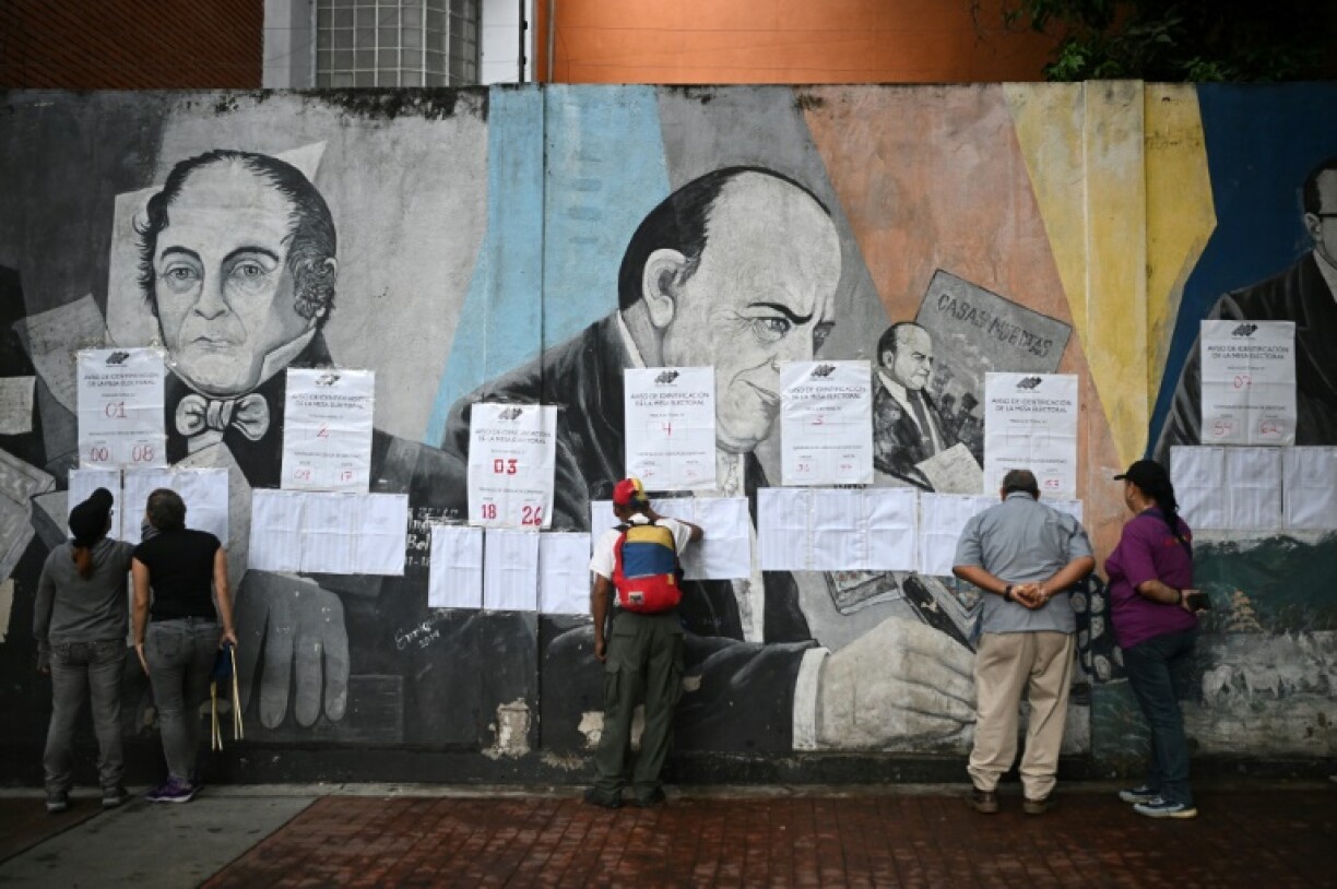 Des électeurs regardent les listes électorales devant un bureau de vote à Caracas, lors des élections pour élire députés et gouverneurs, le 25 mai 2025 au Venezuela