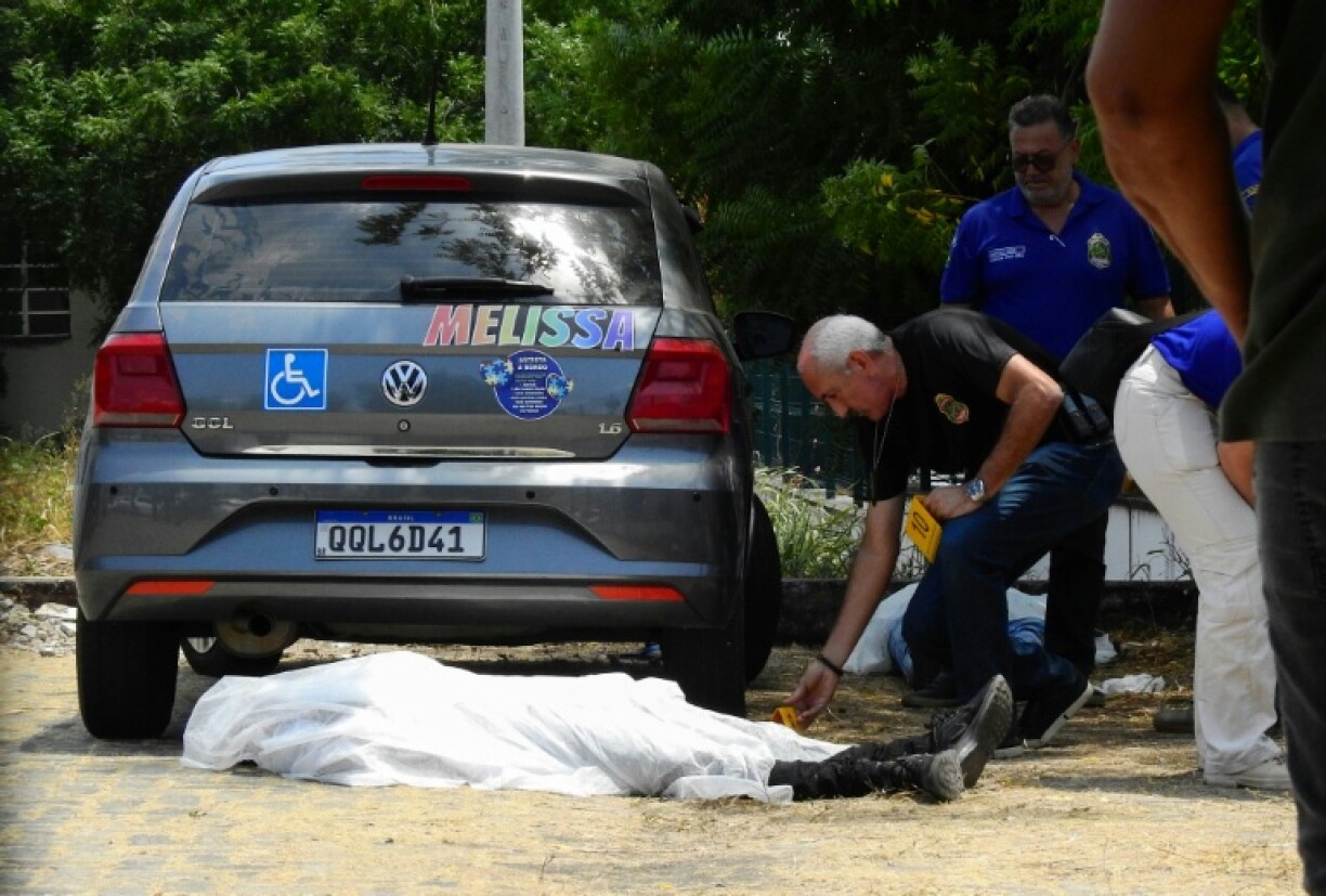 Ceara's civil police officers check the bodies of two teenagers killed in a shooting inside a public school parking lot