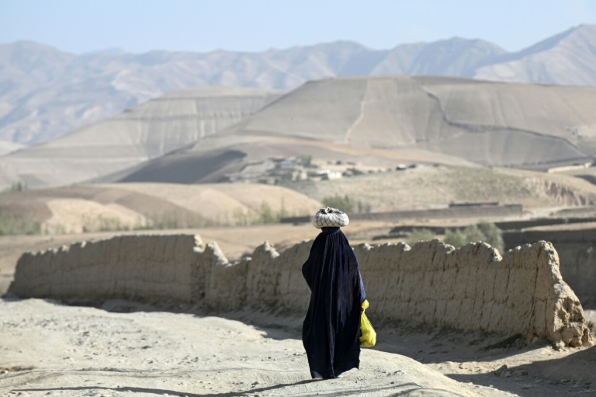 An Afghan burqa-clad woman walking along a road in the Argo district of Afghanistan's Badakhshan province
