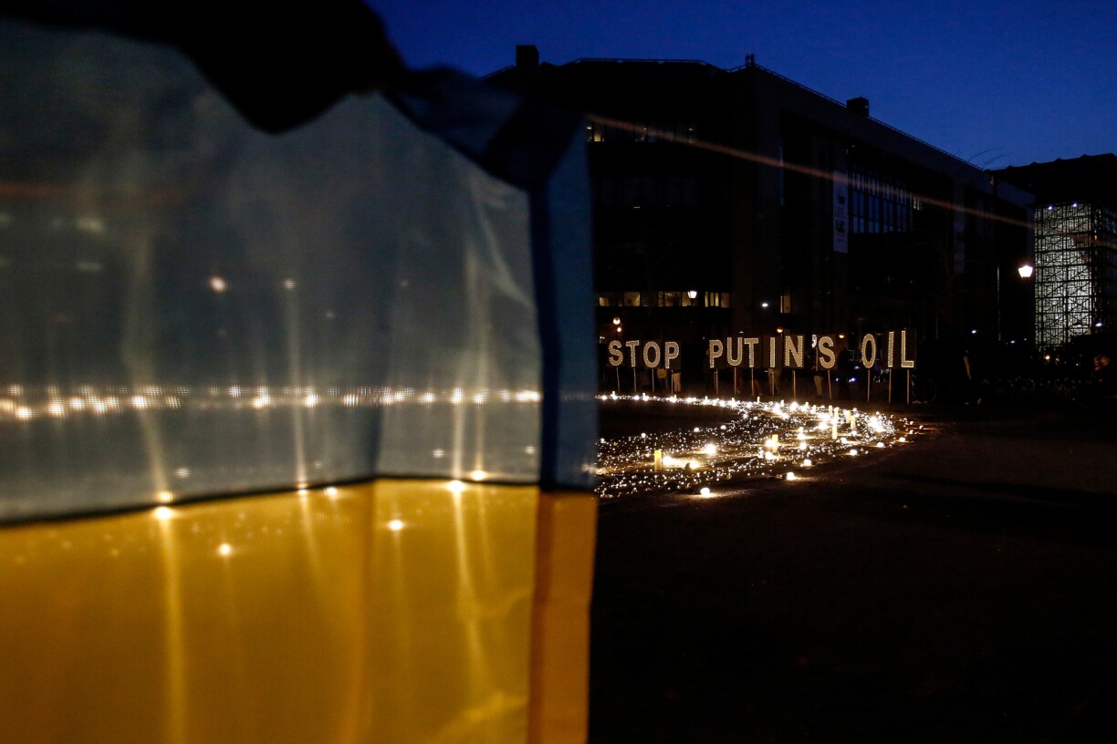 A demonstrator holds an Ukrainian flag in front of a sign reading