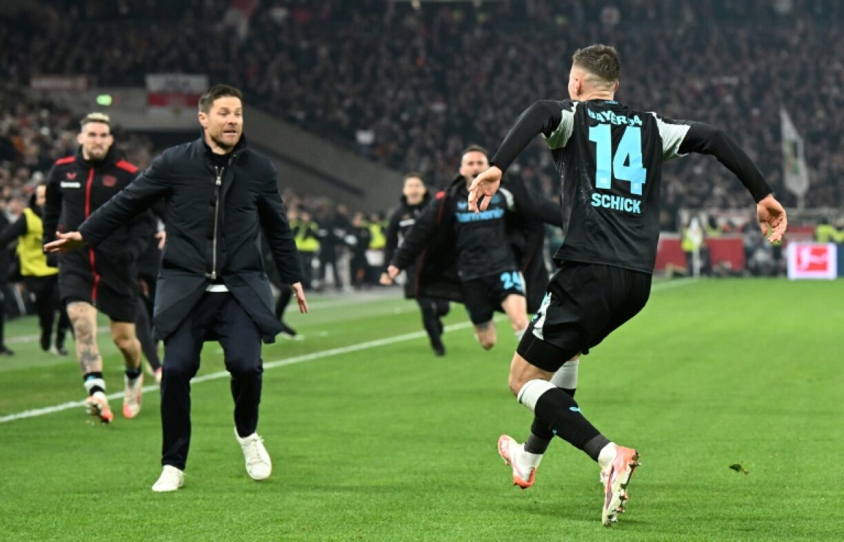 Bayer Leverkusen coach Xabi Alonso runs onto the field to celebrate with Patrik Schick after the striker's stoppage-time winner