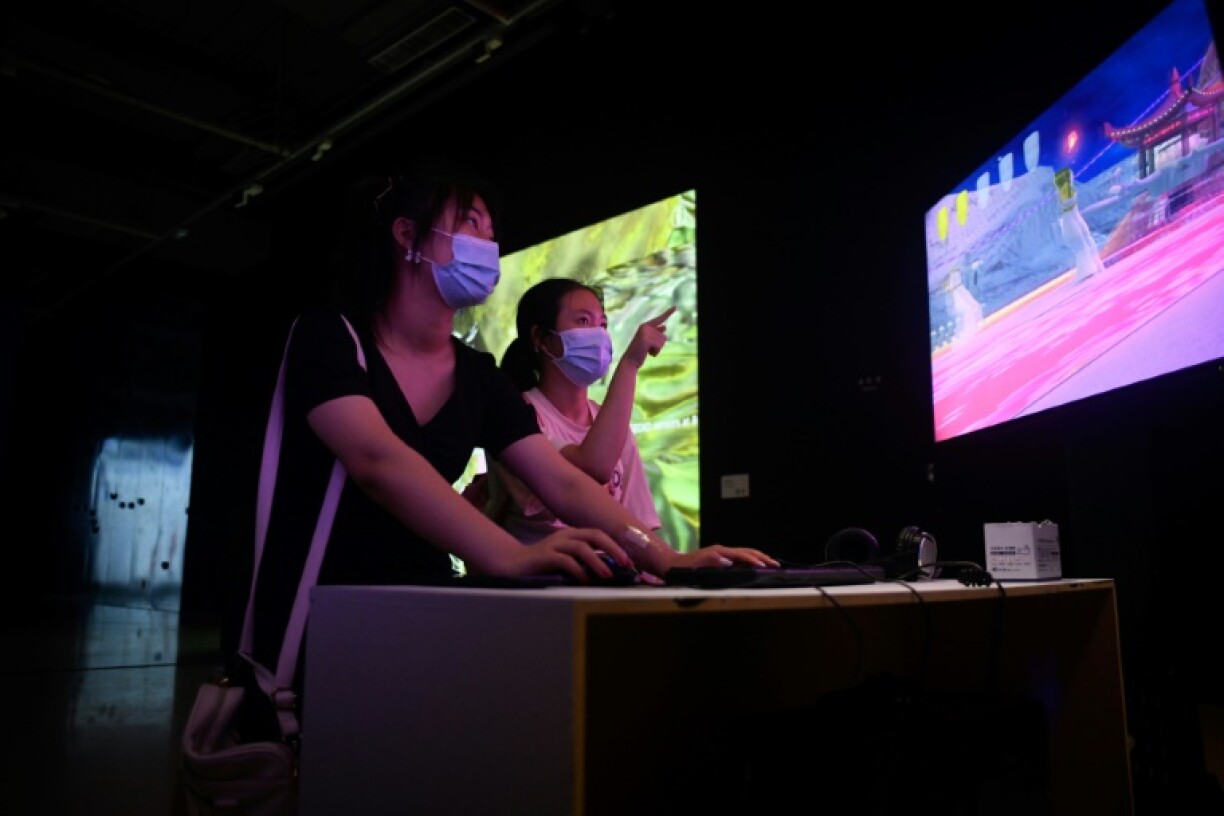 Deux jeunes filles jouent à des jeux vidéos lors de leur visite d'une exposition sur l'art numérique au musée de Pékin, le 12 août 2021