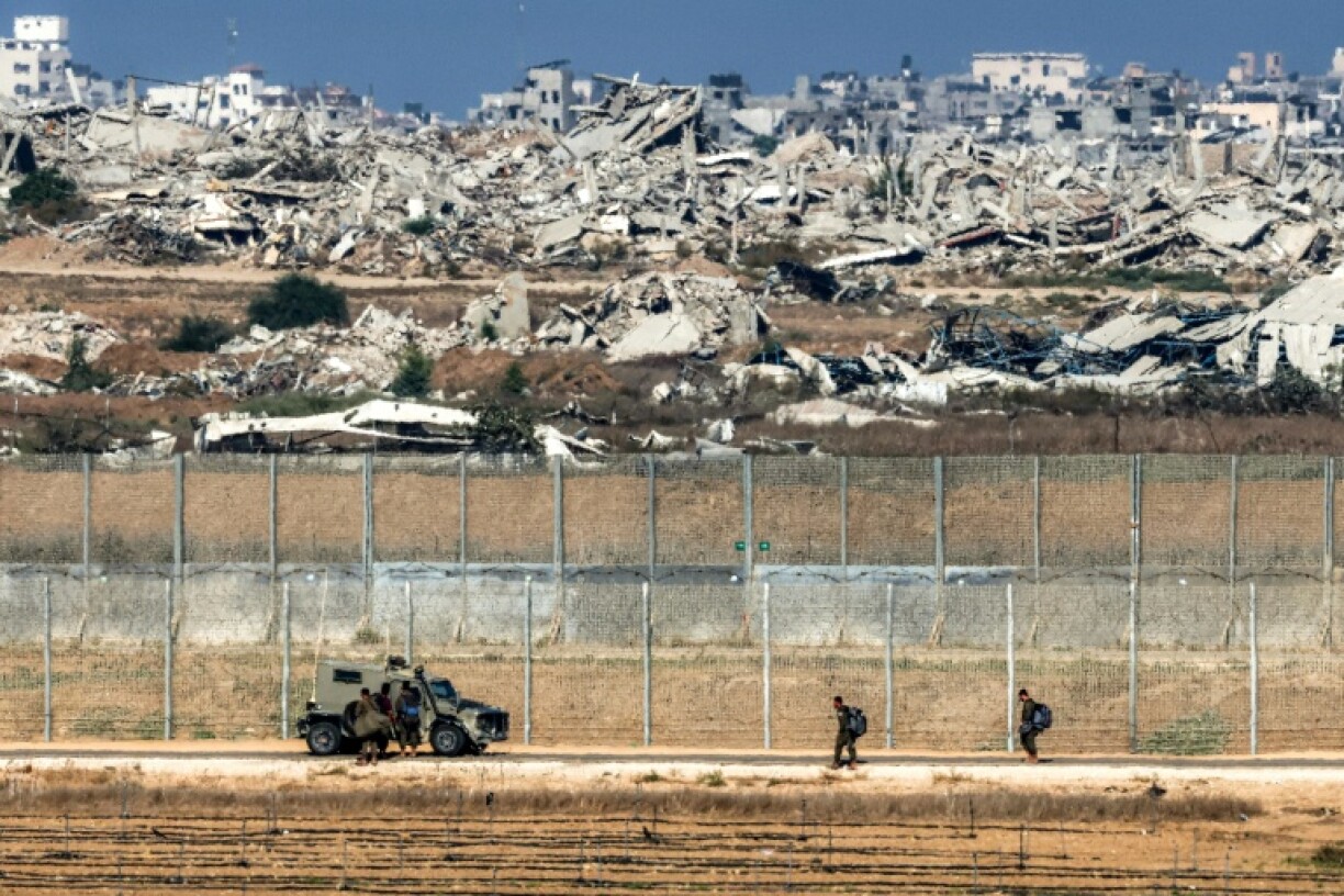Israeli army soldiers walk towards an armoured vehicle at a position along the border fence with the Gaza Strip in southern Israel