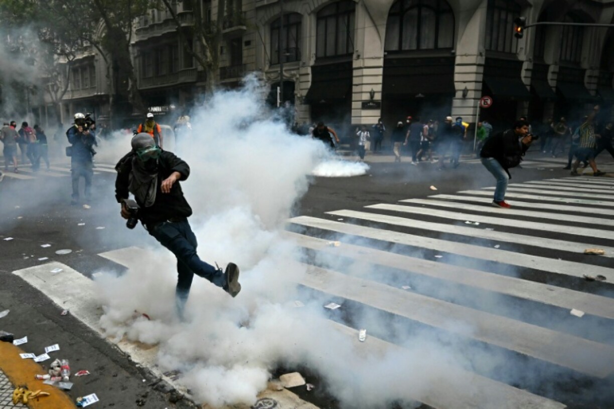 A demonstrator kicks a tear gas canister during a protest of pensioners supported by football fans against the government of President Javier Milei