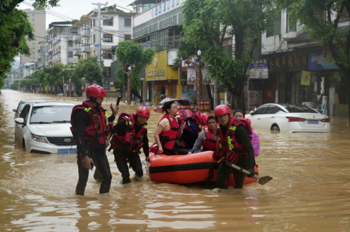 Rescuers help evacuate residents from a flooded street in Rongjiang, in China's southwest Guizhou province on June 24