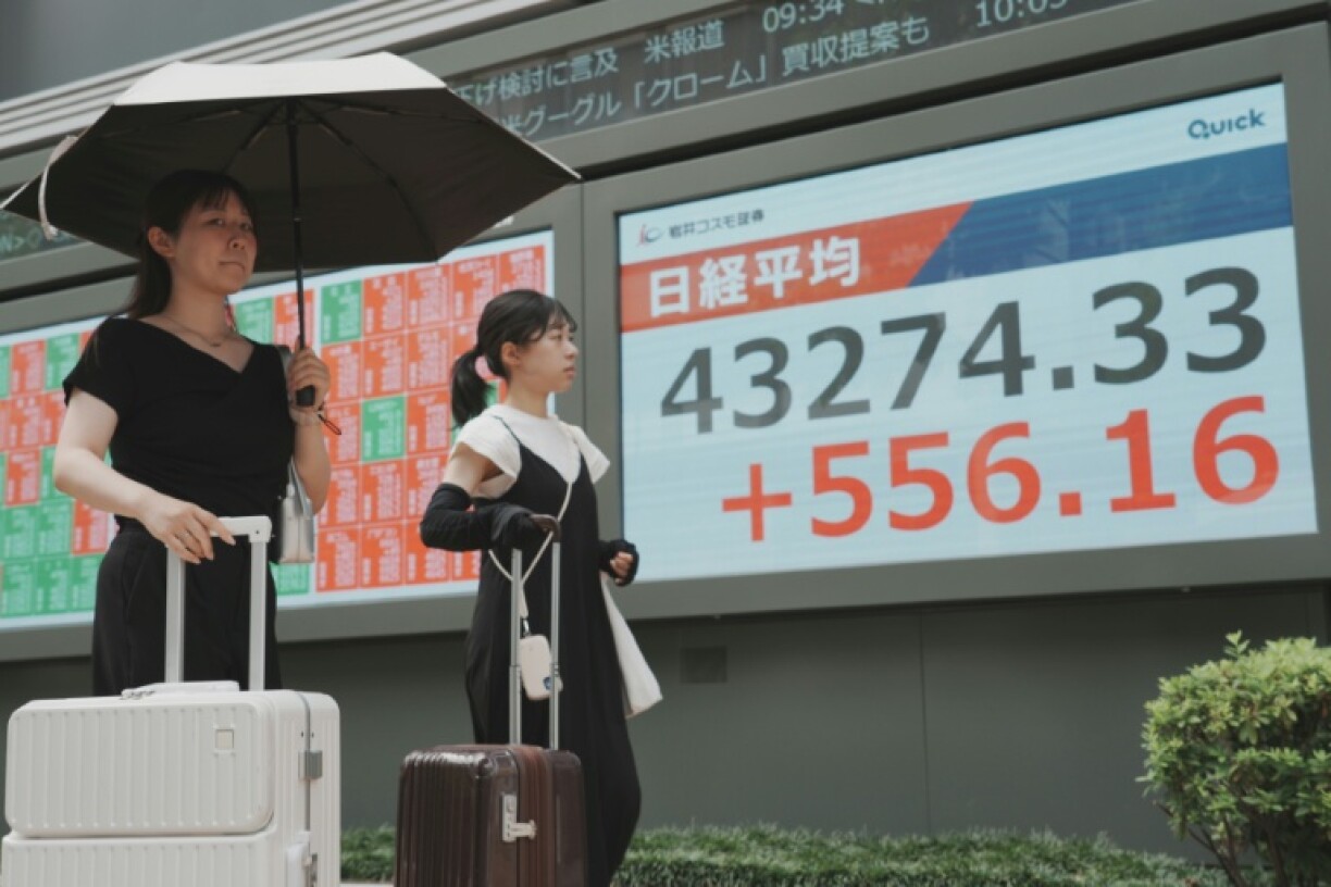 Pedestrians walk past an electronic quotation board displaying the Nikkei Stock Average on Wednesday