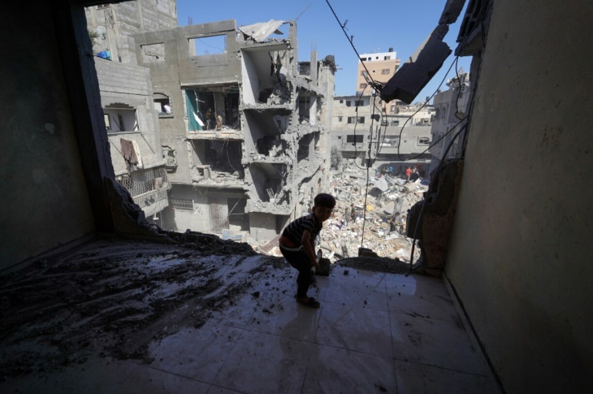 Un garçon palestinien aide à déblayer les gravats dans un immeuble endommagé par une frappe israélienne au milieu des destructions dans le camp de réfugiés d'al-Bureij, dans le centre de la bande de Gaza, le 18 juin 2024