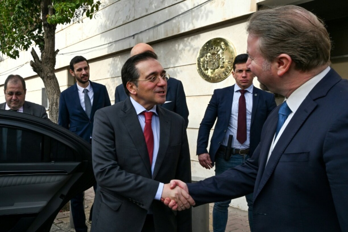 Spain's Foreign Minister Jose Manuel Albares (L) shakes hands with an official outside Madrid's reopened embassy in Damascus