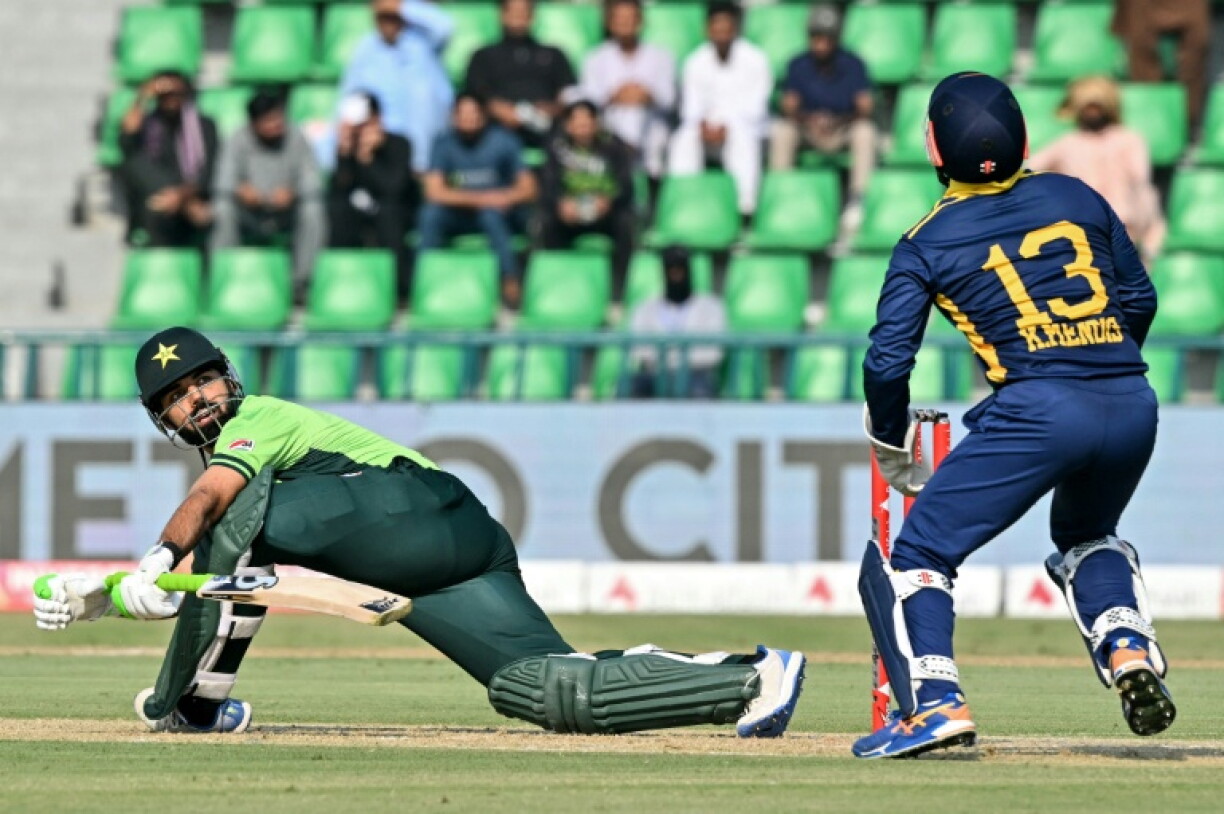 Pakistan's Shadab Khan looks back after playing a shot as Sri Lanka's wicketkeeper and captain Kusal Mendis prepares to take a catch during their match at the Gaddafi Stadium in Lahore
