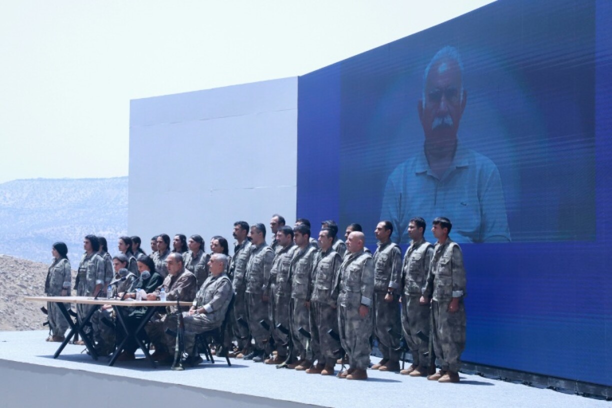 Standing under a giant screen showing a picture of the PKK's jailed founder Abdullah Ocalan, the fighters read out a statement before laying down their weapons