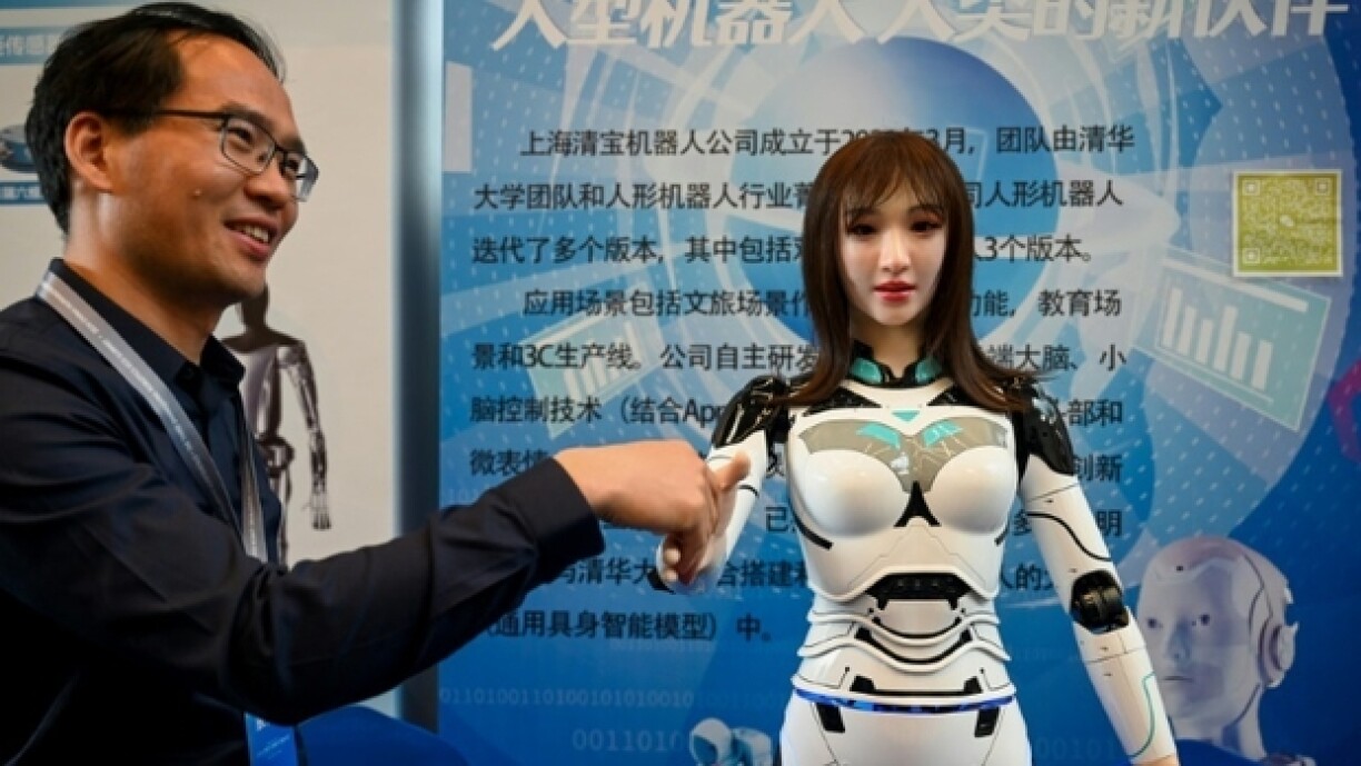 Un exposant serre la main d'un robot humanoïde lors de l'édition 2024 du Salon des concepteurs de robots humanoïdes, à Shanghai (Chine) le 6 juin 2024.